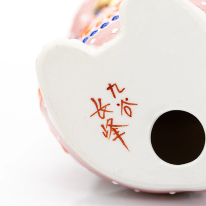 Underside of the pink cat with a red maker's inscription and round opening.