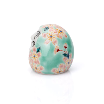 Angled view of the cherry blossom daruma and its white face.