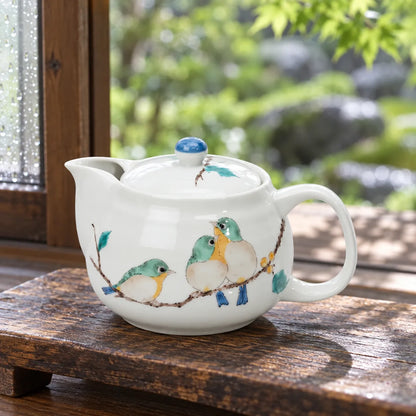 Seikou Kutani teapot with three painted mejiro birds beside a garden window