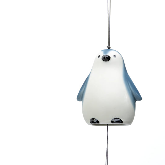 White and blue penguin wind chime hanging by its cord on white.