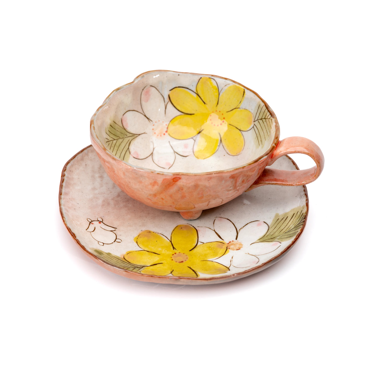 Angled view into the orange cup's floral interior and matching saucer.