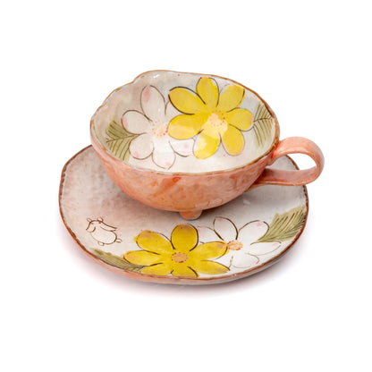 Angled view into the orange cup's floral interior and matching saucer.