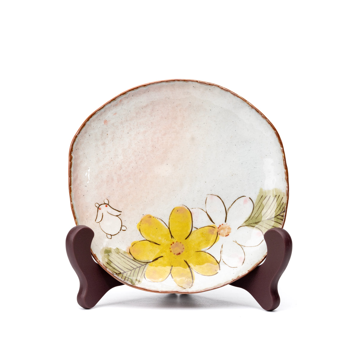 Matching floral and rabbit saucer displayed upright on a small stand.