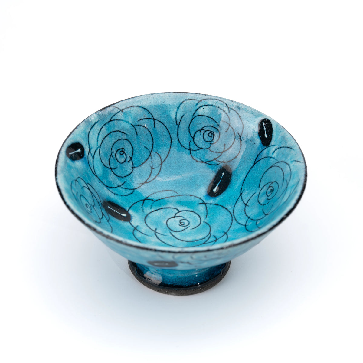 Angled top view of the turquoise bowl and its outlined rose pattern.