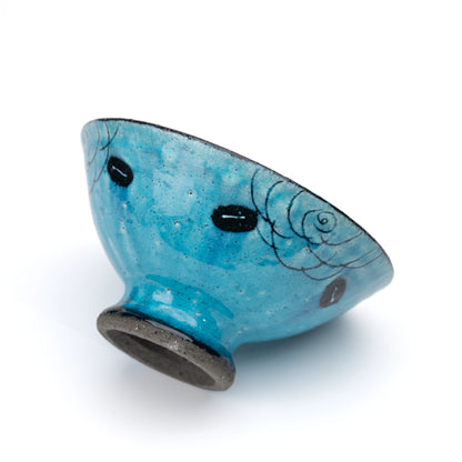 Side view of the turquoise footed dessert bowl and black foot.