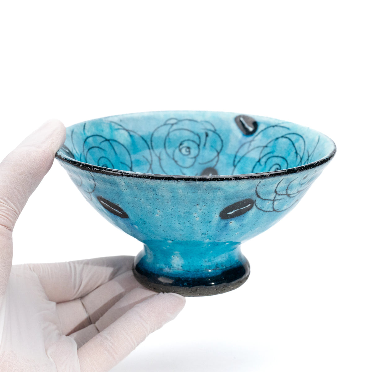 Turquoise rose dessert bowl held in a gloved hand.