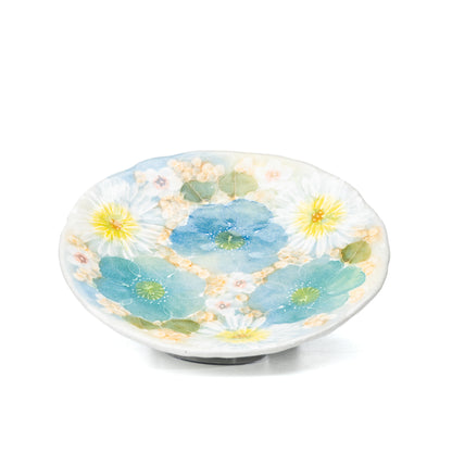 Floral saucer with blue and yellow flowers viewed from above.