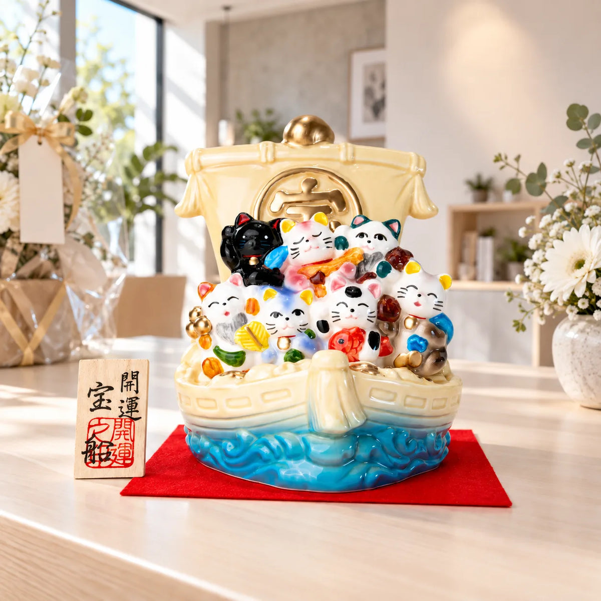 Seto seven-cat treasure ship on its red display cloth with wooden plaque at a studio celebration