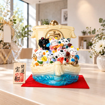 Seto seven-cat treasure ship on its red display cloth with wooden plaque at a studio celebration