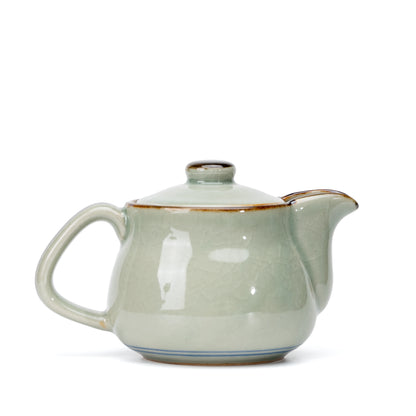 Plain reverse of the gray-green teapot and its curved spout.