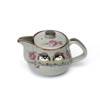 Gray-green Kutani teapot with two sparrows, pink blossoms and a brown rim on white.