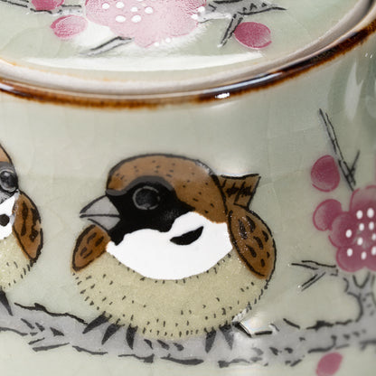 Close-up of a painted sparrow among pink blossoms.