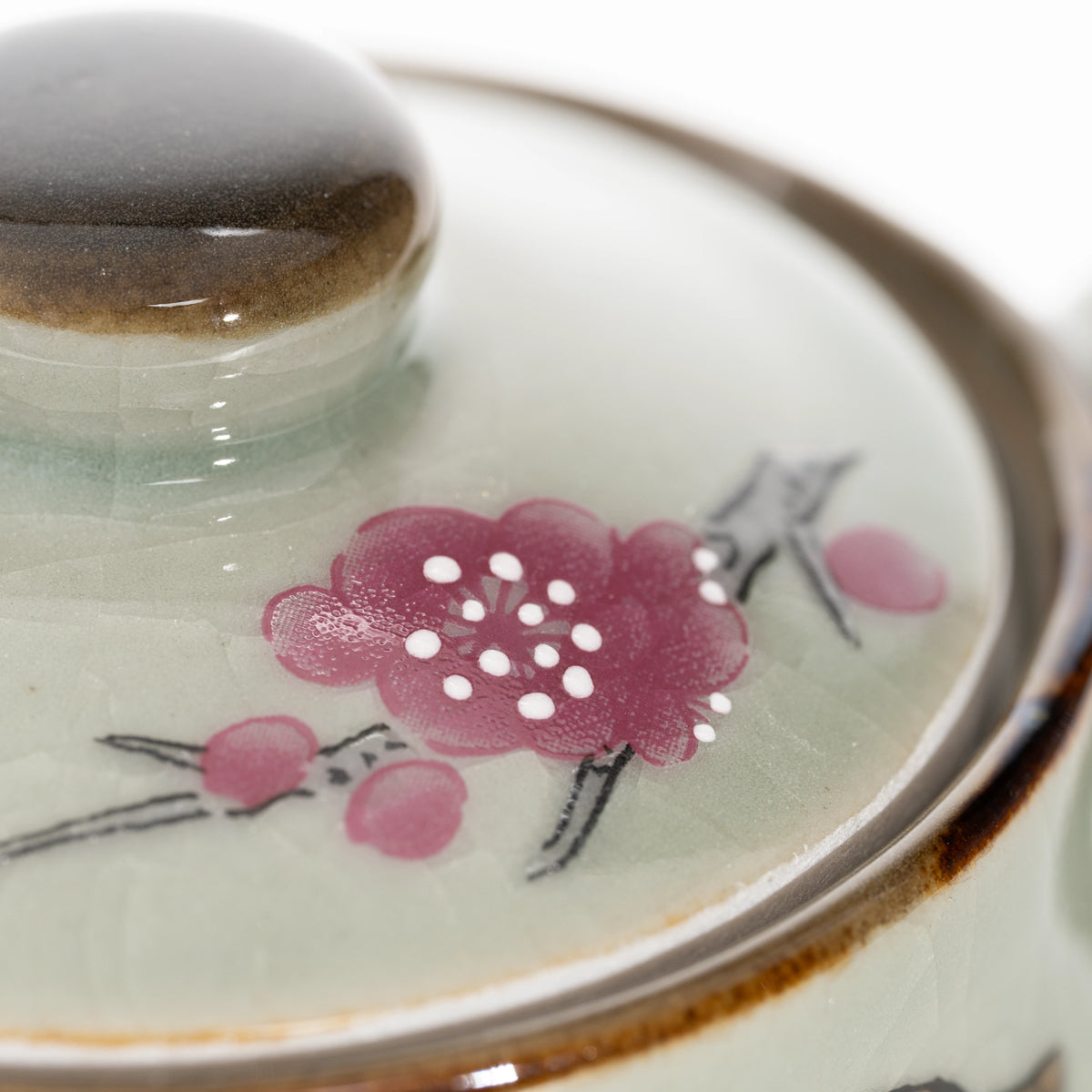 Pink floral decoration and brown rim on the teapot lid.