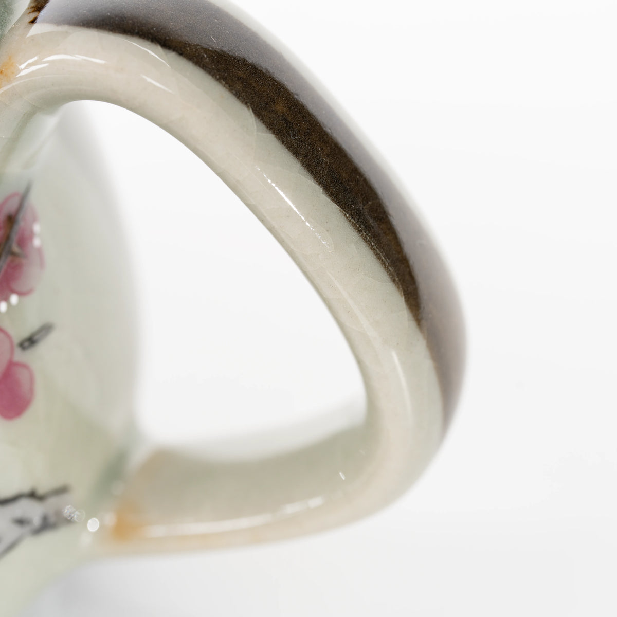 Curved teapot handle with brown edging.