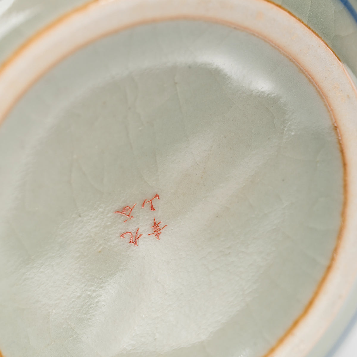 Red maker's mark on the glazed underside of the teapot.
