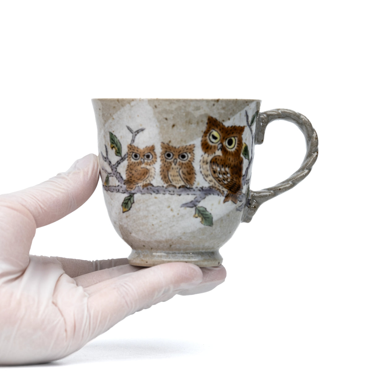 Kutani three owls mug held in a gloved hand to show scale.