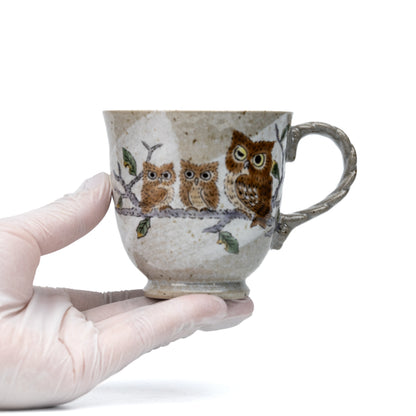 Kutani three owls mug held in a gloved hand to show scale.
