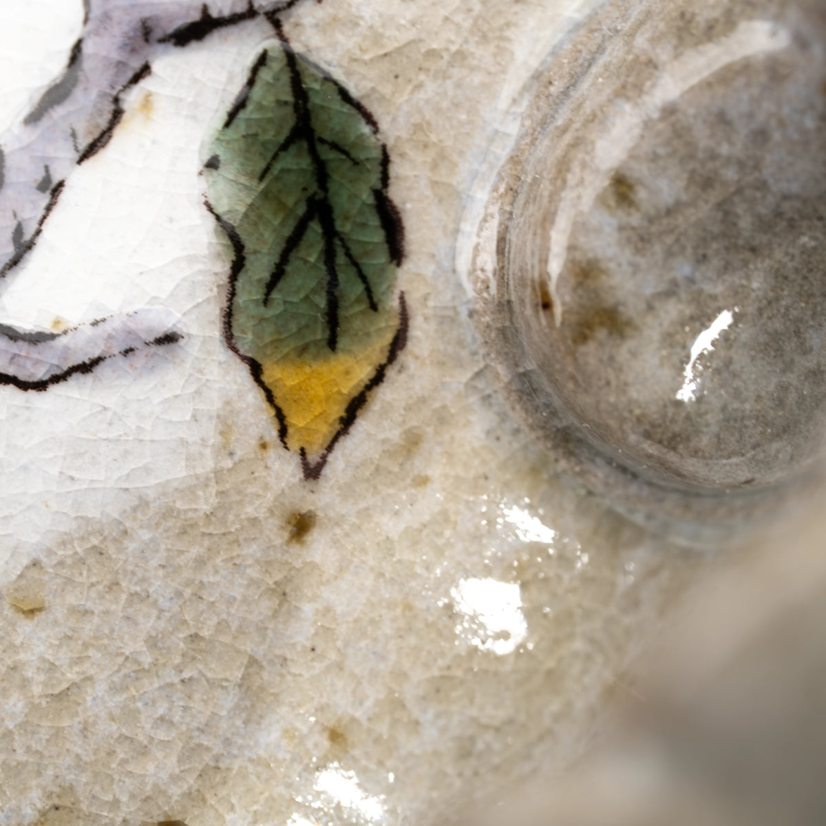 Close-up of a painted leaf beside the mug's textured handle.