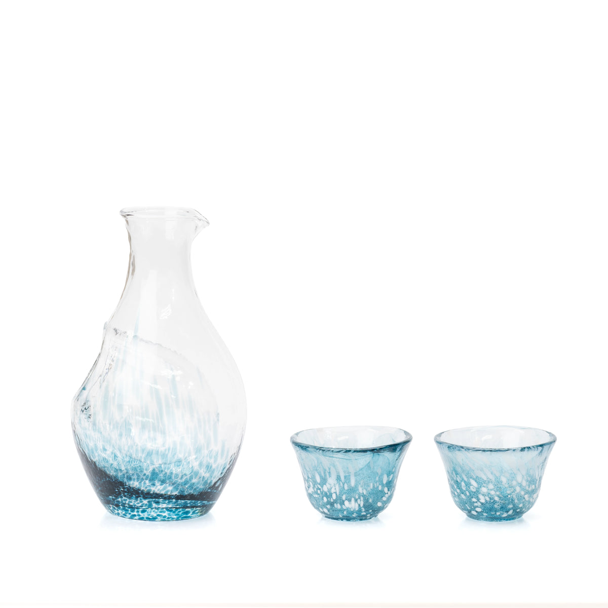 Blue glass sake carafe with an ice pocket and two matching cups on white.