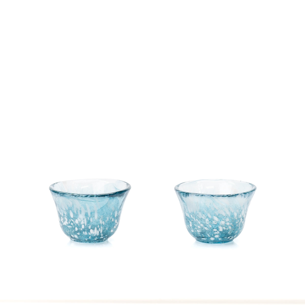 Two small blue glass sake cups on white.