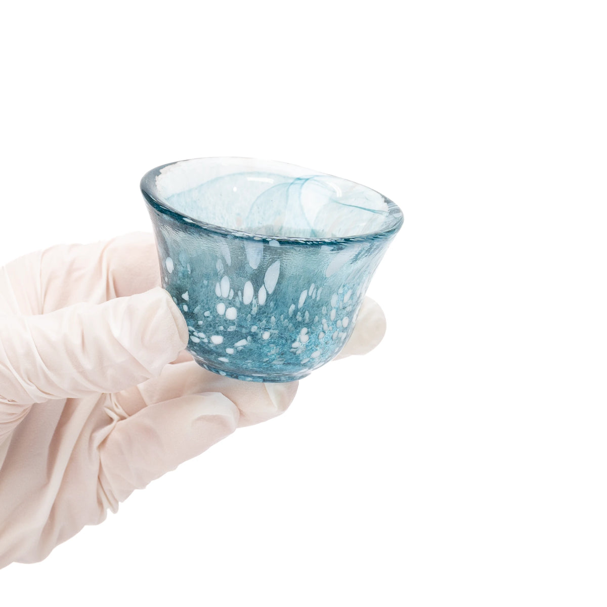 Small blue glass sake cup held in a gloved hand.
