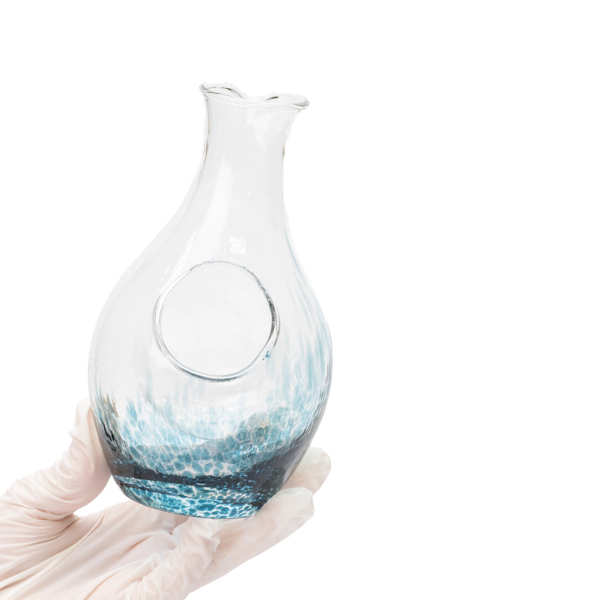 Blue glass carafe held in a gloved hand, showing its round ice pocket.