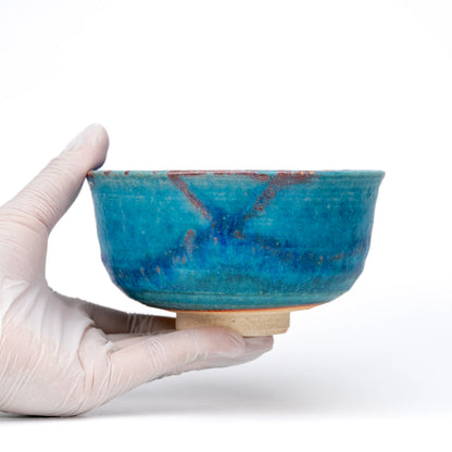 Blue matcha bowl held in a gloved hand.
