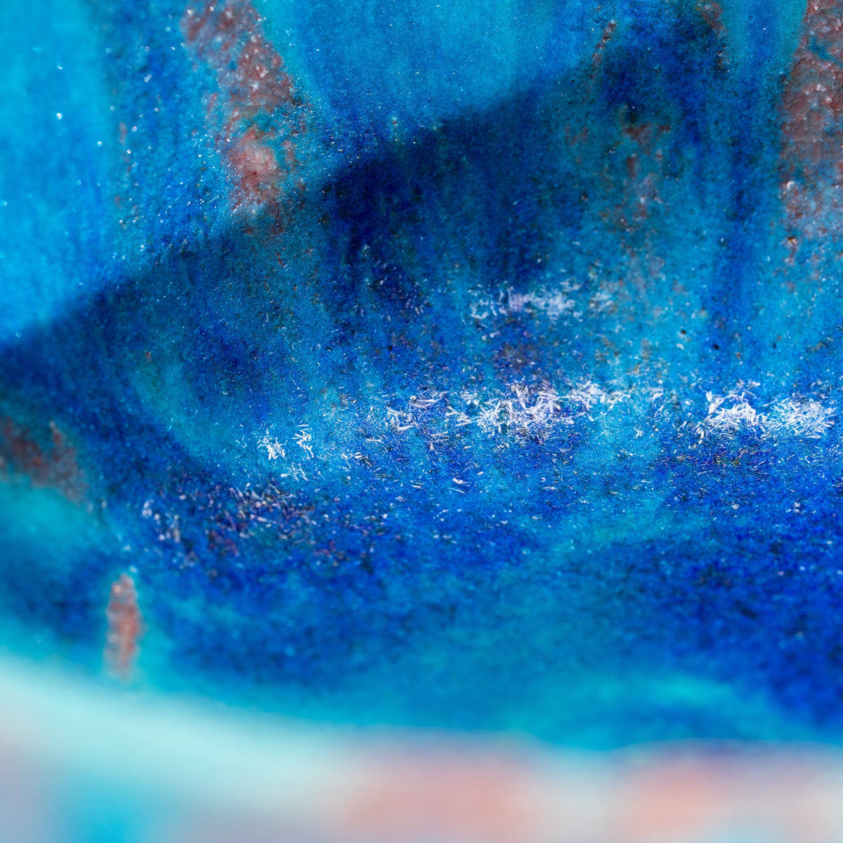 Close-up of layered blue and purple-brown glaze inside the bowl.