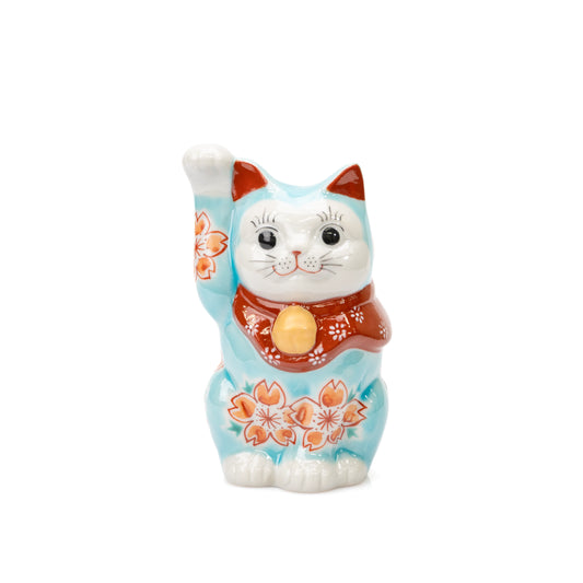 Turquoise Kutani lucky cat with raised right paw, cherry blossoms and a red bib on white.