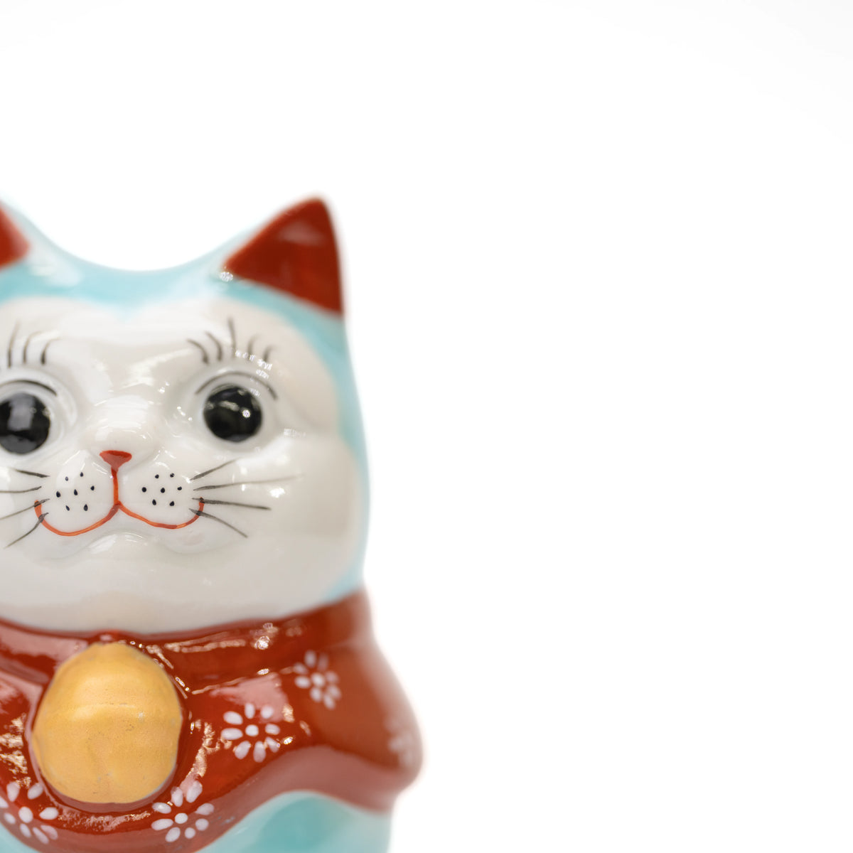 Close-up of the turquoise lucky cat's face and red bib.