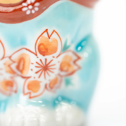 Peach-colored cherry blossom painted on turquoise glaze.