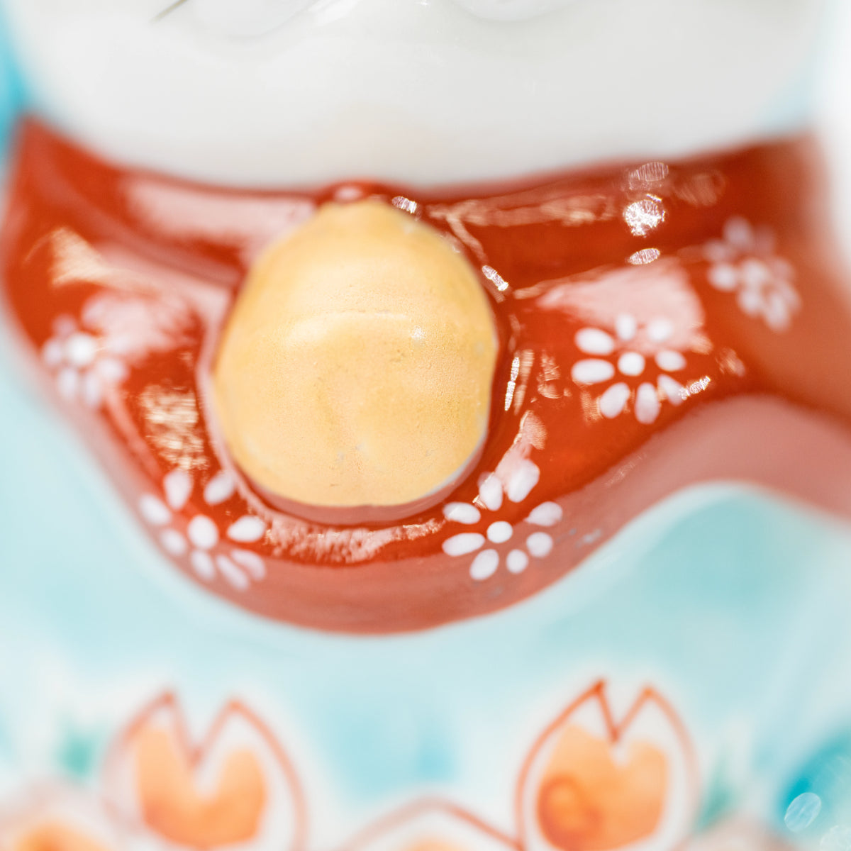 Golden-colored bell and red floral bib on the turquoise cat.