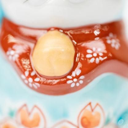 Golden-colored bell and red floral bib on the turquoise cat.