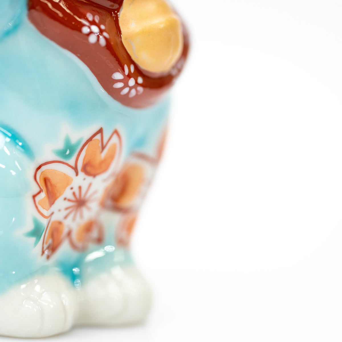 Side detail of the turquoise lucky cat and white feet.