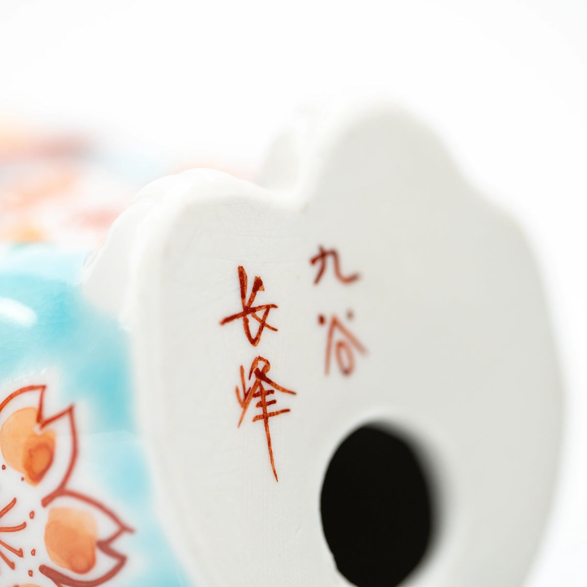 Red maker's inscription and opening on the turquoise cat's underside.