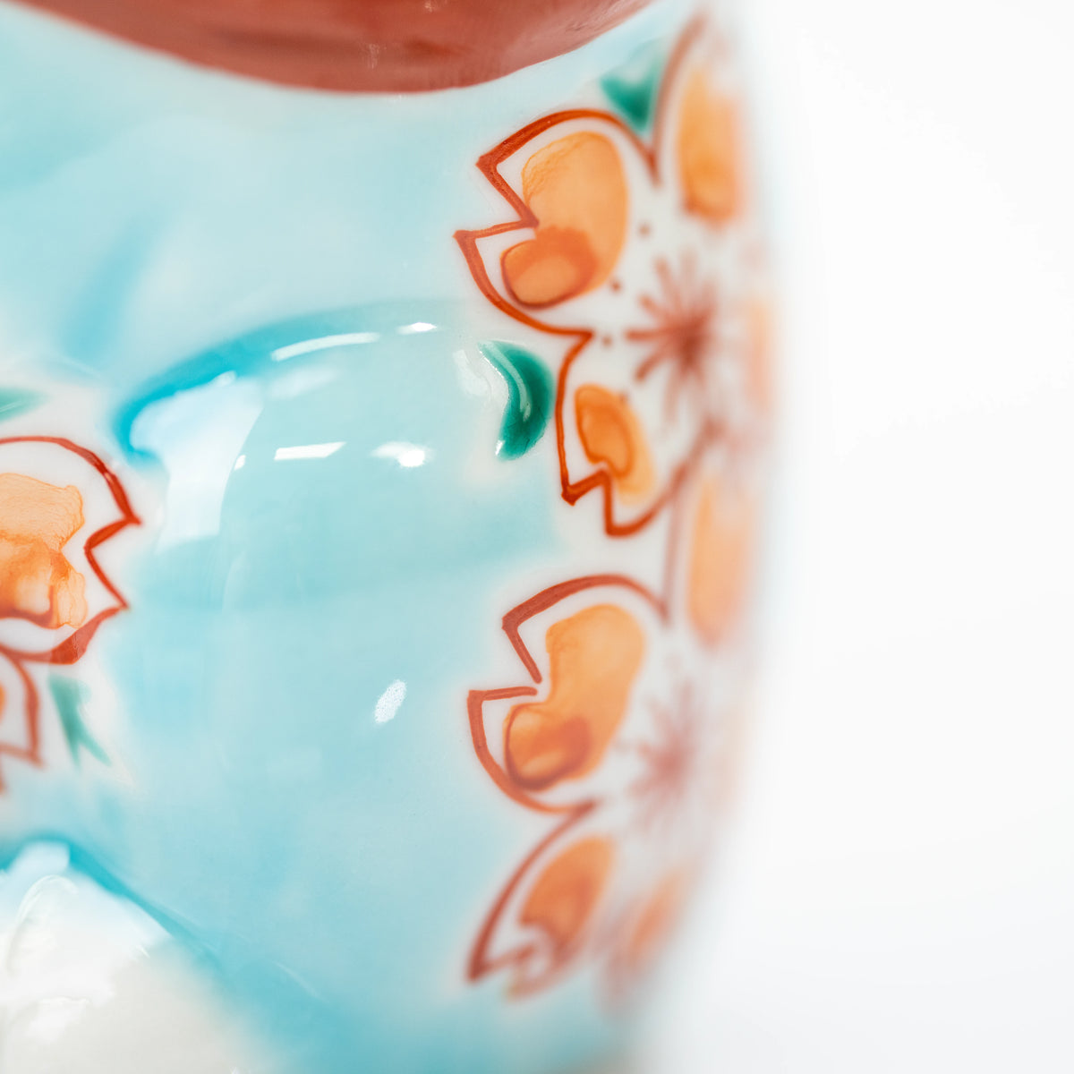 Cherry blossom details beneath glossy turquoise glaze.