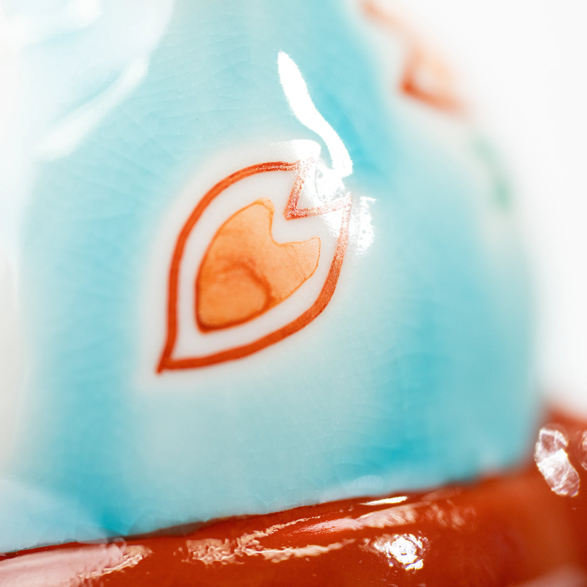 Small peach-colored petal above the red bow on the turquoise cat.