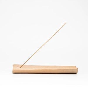 Warm brown Hechimon incense holder with an incense stick on a white background.