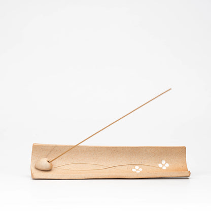 Top view of the incense tray with white flowers and fine curved stems.