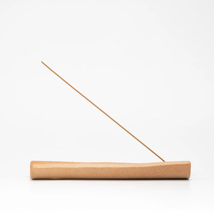 Side view of the long brown incense holder and incense stick.
