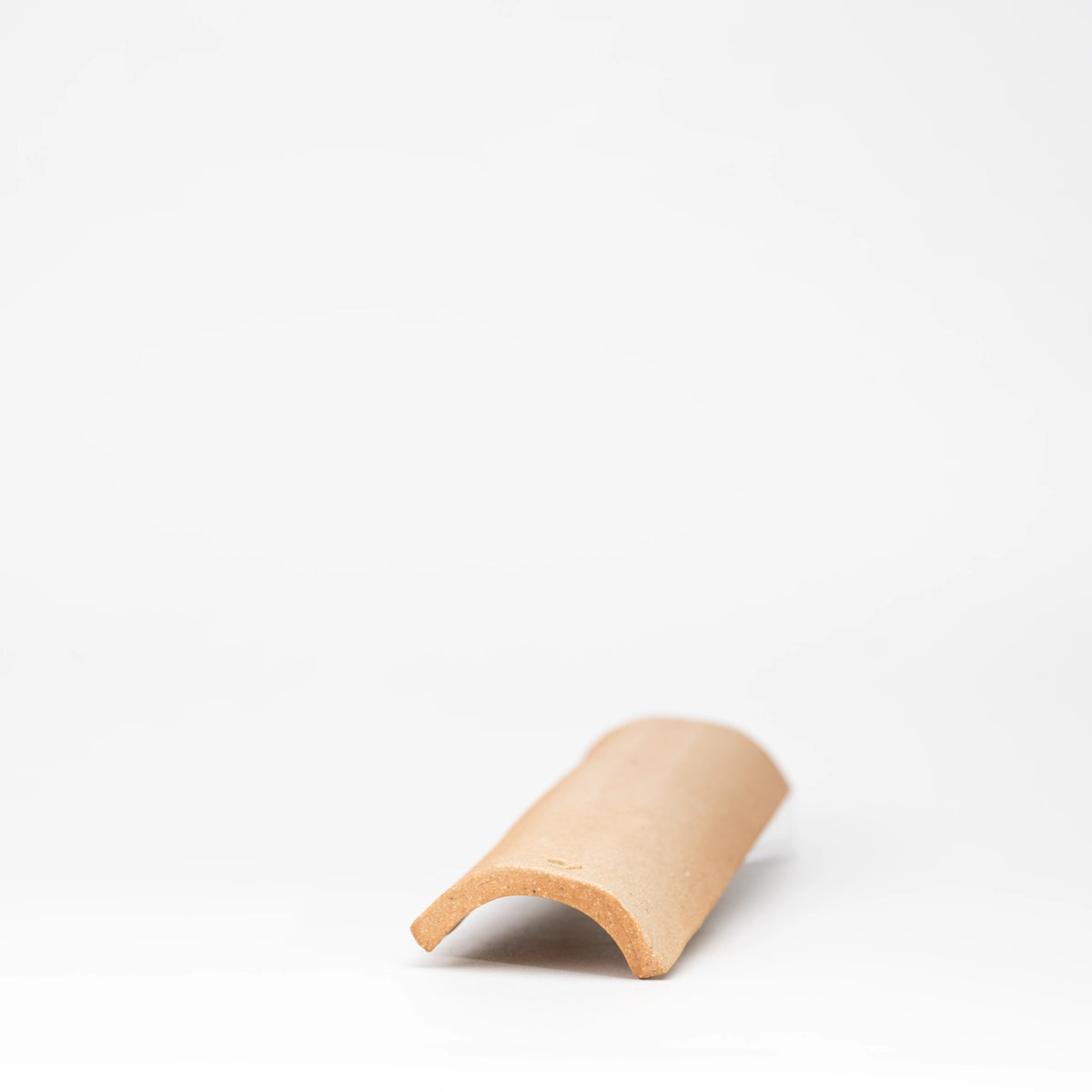 Underside of the curved brown ceramic incense tray.
