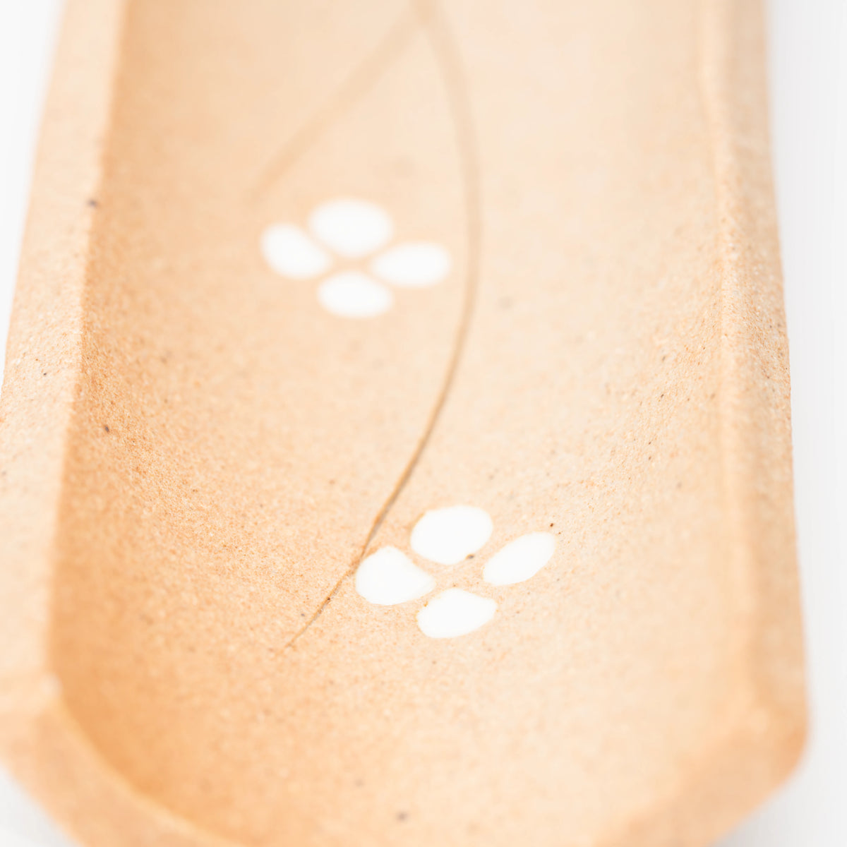 Close-up of white four-petalled flowers on the brown incense tray.