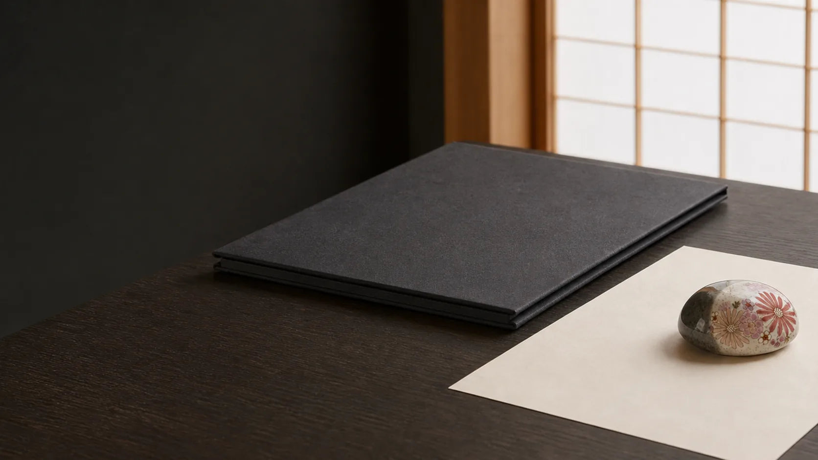 A minimal studio desk with a closed document folder and ceramic paperweight.